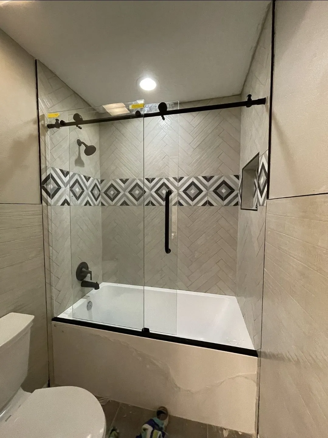 Finished tiled walk-in shower with a glass enclosure and a decorative tile band