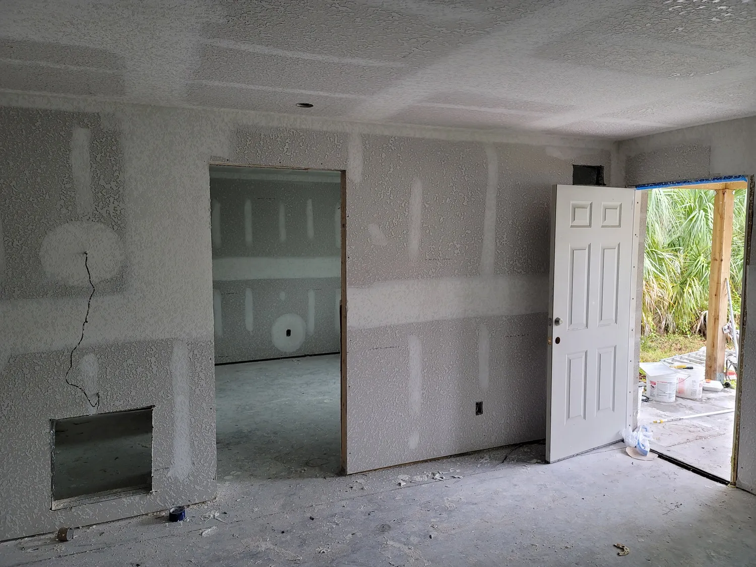 Multi-room drywall installation in progress with hung and taped board across the walls