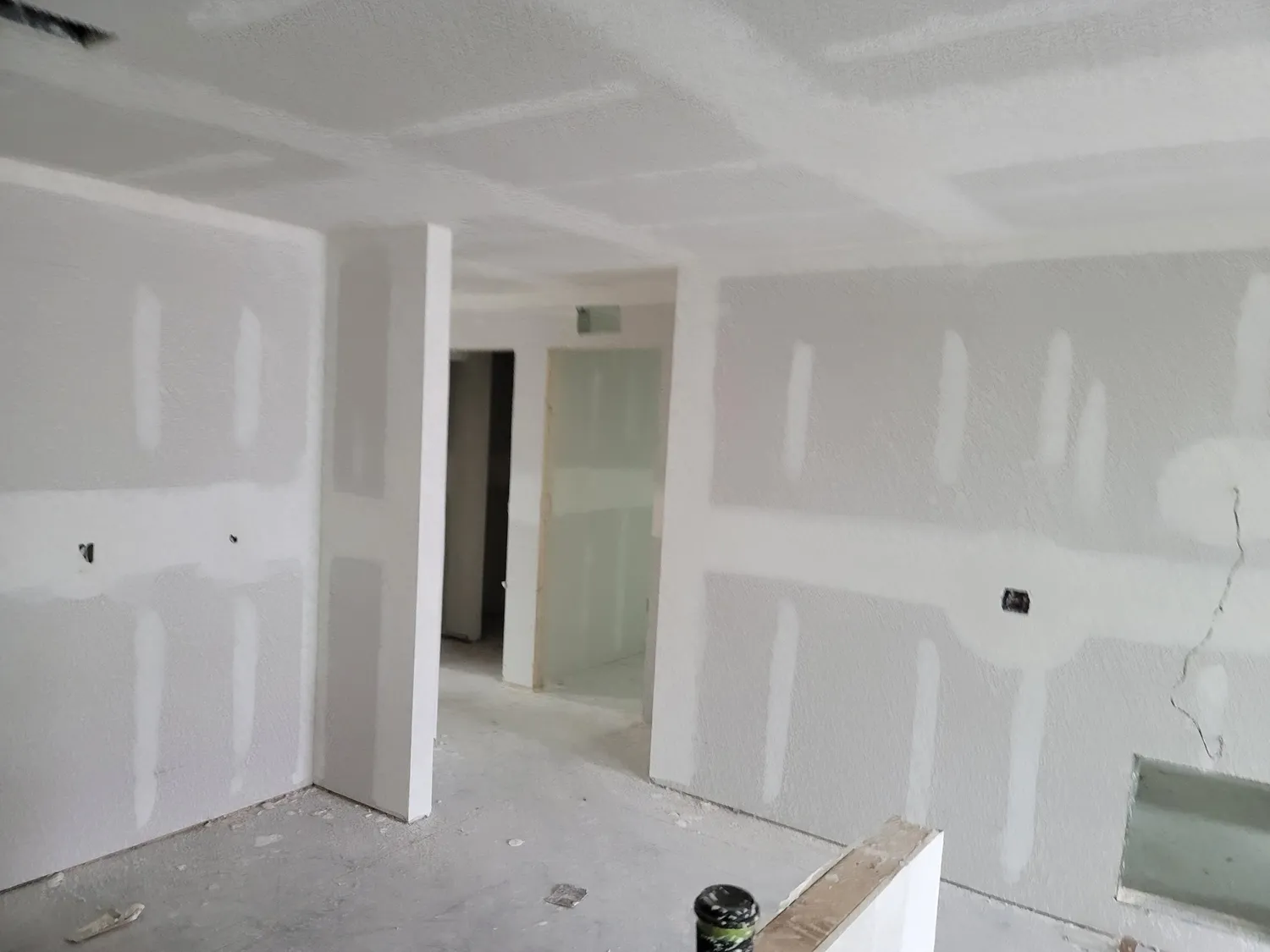 Interior drywall progress showing a finished ceiling and prepped wall surfaces