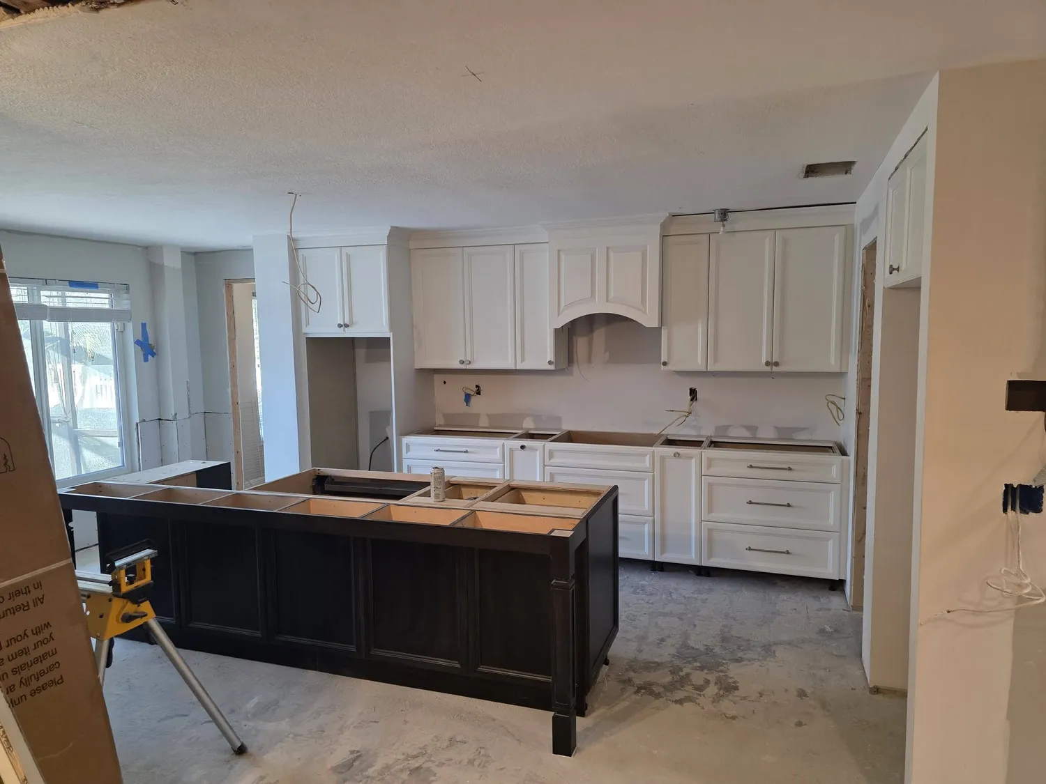 Hildebrand crew installing white shaker cabinets and an island during a kitchen remodel