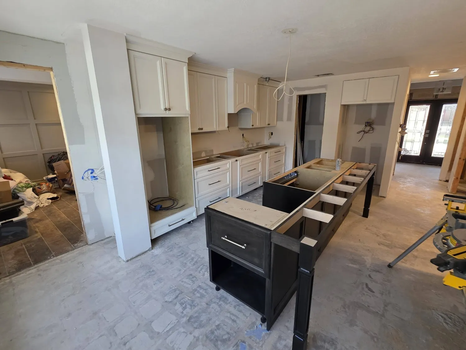 Kitchen remodel showing freshly installed white cabinetry along the perimeter wall