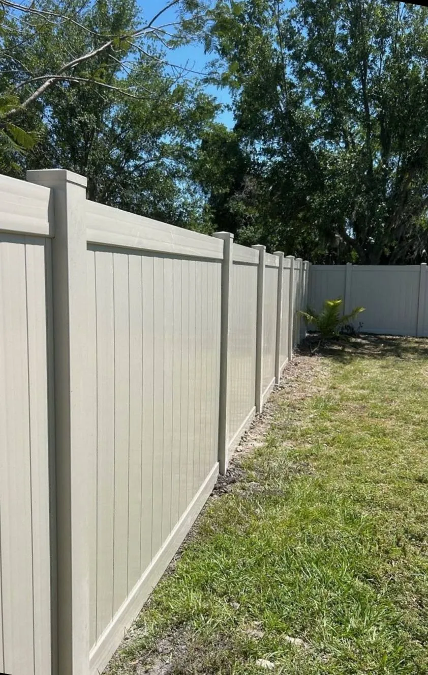 New tan vinyl privacy fence running along the side of a Manatee County backyard