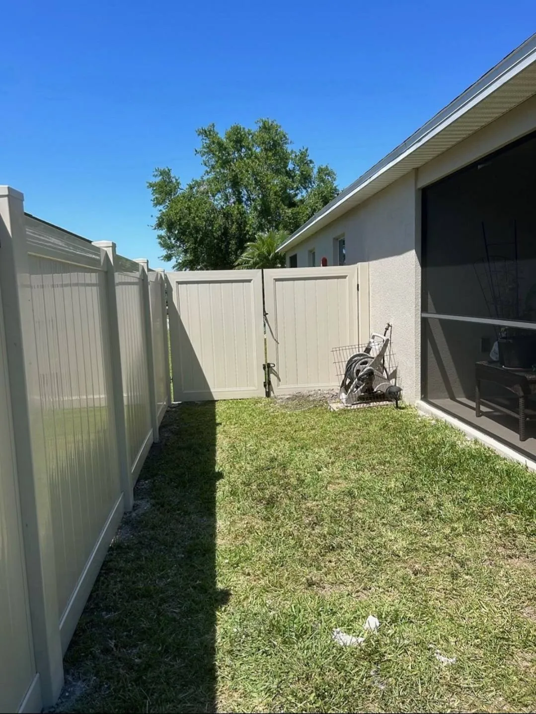 Tan vinyl fence with a clean corner section in a Florida backyard