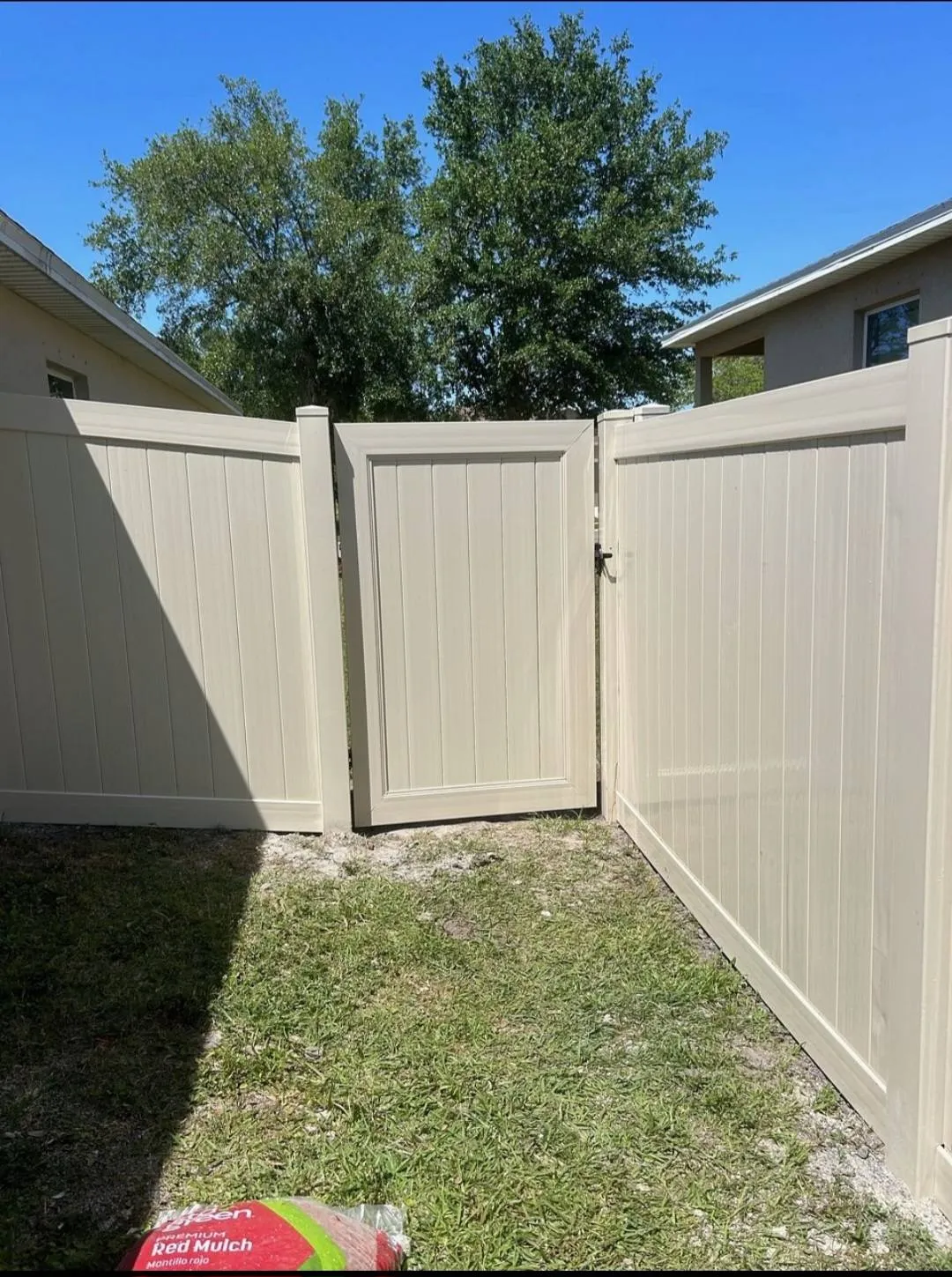 New tan vinyl fence line bordering a maintained residential lawn