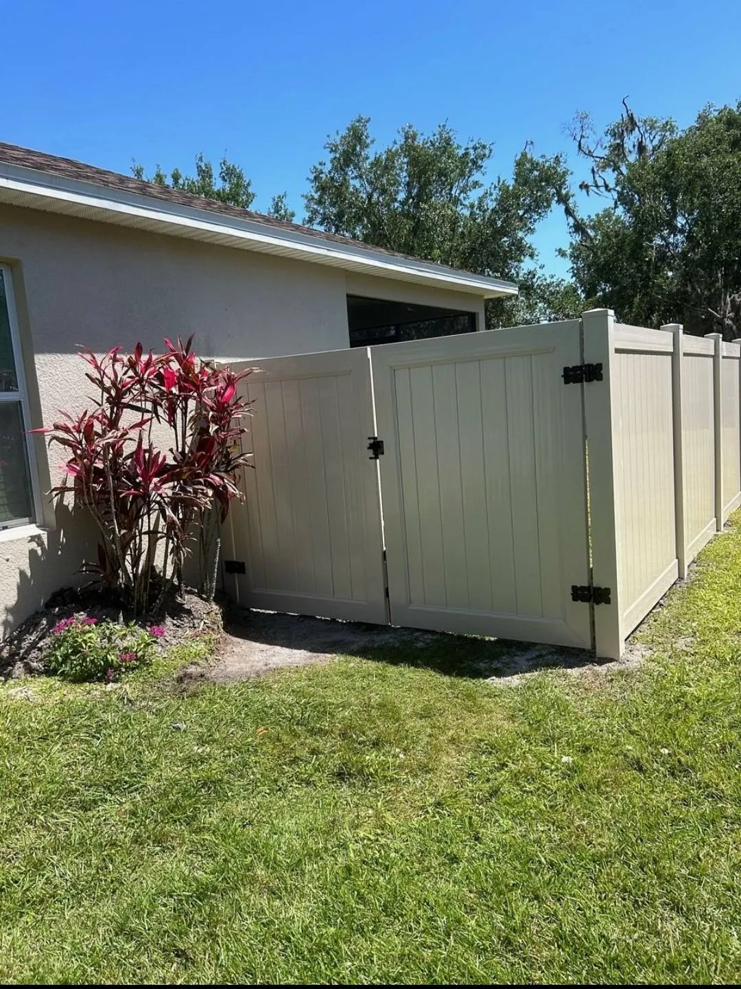 Completed tan vinyl privacy fence with a matching gate section